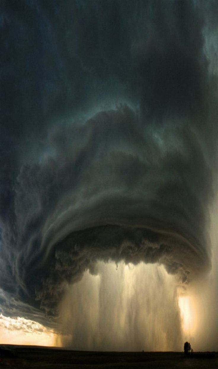 a dramatic and powerful storm cloud, with a dark, menacing, swirling shape, hangs low over a flat landscape. heavy rain pours down from the cloud, creating a curtain of water. the cloud is dark and ominous, with swirling patterns that suggest a sense of power and danger. the rain is heavy and relentless, making the scene feel both aweinspiring and slightly threatening. the overall effect is a striking reminder of the power of nature.