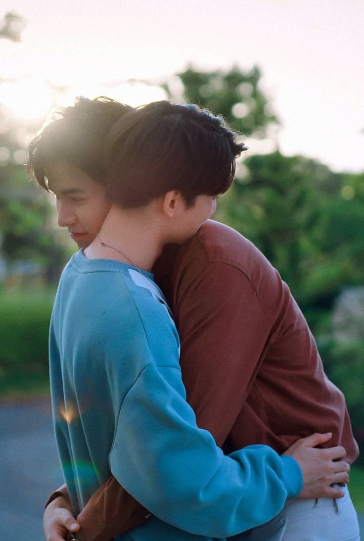two men are hugging each other in an embrace, showcasing affection and love. the man in the blue sweater