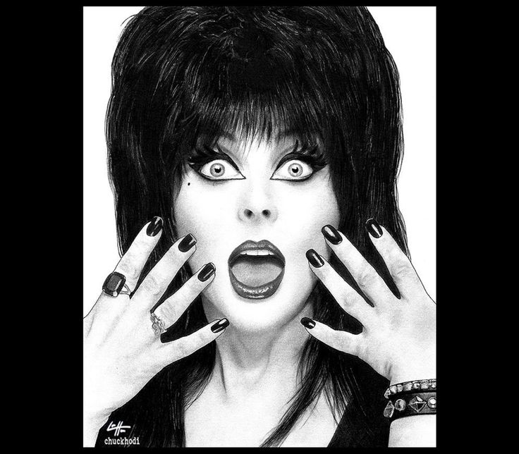 a black and white portrait of a woman with black hair, black clothing, and dark makeup. she is looking at the viewer with a surprised expression. her mouth is open wide and her eyes are staring. she is wearing several rings on her fingers, and a bracelet on her wrist.