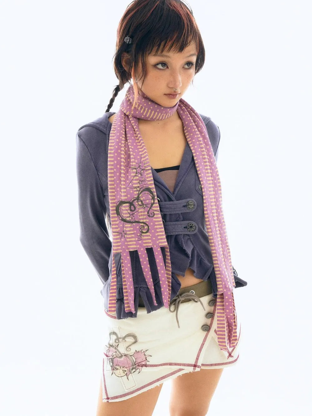 a young asian woman with dark hair styled in a side braid and bangs is wearing a stylish outfit. she has on a purple polka dot and striped scarf, a purple cardigan or jacket, and a creamcolored miniskirt with an illustration on it. the skirt features a design that seems to be inspired by anime or manga styles. she is posing against a bright white background, and the image has a clean and welllit feel. the overall look is casual, yet trendy and fashionable, with elements that are both cute and stylish.