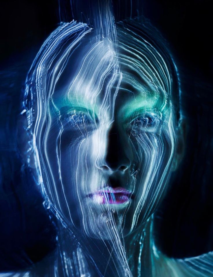 the image is a striking piece of light painting art depicting a woman's face.  the face is not clearly defined, but rather appears as a composite of glowing, swirling lines of light in shades of blue, teal, and green.  these light trails create an ethereal, almost otherworldly effect, giving the impression of energy or data flowing around and through the subject's features. the background is dark, focusing all attention on the brightly lit, abstract facial structure. the overall style is futuristic and surreal, suggesting a blend of technology and fantasy.