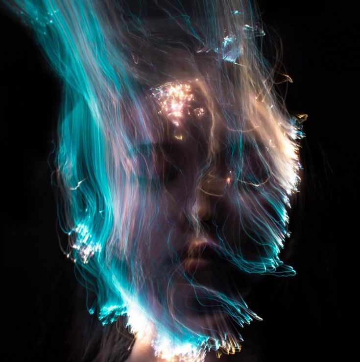a closeup shot of a woman's face, obscured by a swathe of blue and white light. the light appears to be flowing through and around her face, giving the impression of a ghostly apparition. the background is black, making the light even more vibrant and eyecatching. the image is both beautiful and unsettling, suggesting a sense of mystery and intrigue.