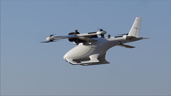 a white drone, with a large body and two sets of propellers, flies in a clear blue sky. the drone has a sleek and modern design, and it appears to be in midflight. the drone is flying towards the right side of the image, and it is clear from the image that it is a sophisticated piece of technology.