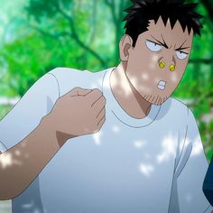 the image shows a man with short dark hair and a surprised expression on his face. he is wearing a white tshirt and has two small, round objects stuck to his nose. he is standing outside in a wooded area, and the lighting suggests that it is a sunny day. the image is a closeup, focusing on the man's face and upper body.