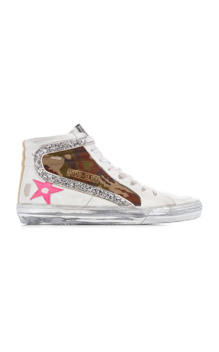 a pair of golden goose slide hightop sneakers are shown in a studio shot against a white background. the shoes are white leather with a camouflage print insert and glitter detailing. they feature a pink star on the side and the golden goose logo is visible. the sneakers are slightly distressed, showing signs of wear that add to their unique character.