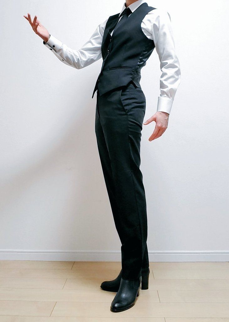a man is standing in a white shirt with a black vest and black pants. he has black boots and is posing with his hand up, looking classy and elegant.
