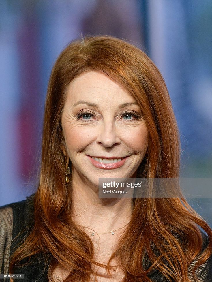 a close up portrait of a smiling woman with long red hair looking at the camera.  she is wearing a black top and has a necklace on.