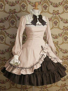 a closeup view of a mannequin dressed in a vintageinspired lolita dress. the dress has a ruffled skirt, long sleeves, and intricate lace detailing.  the dress is primarily light pink and brown.