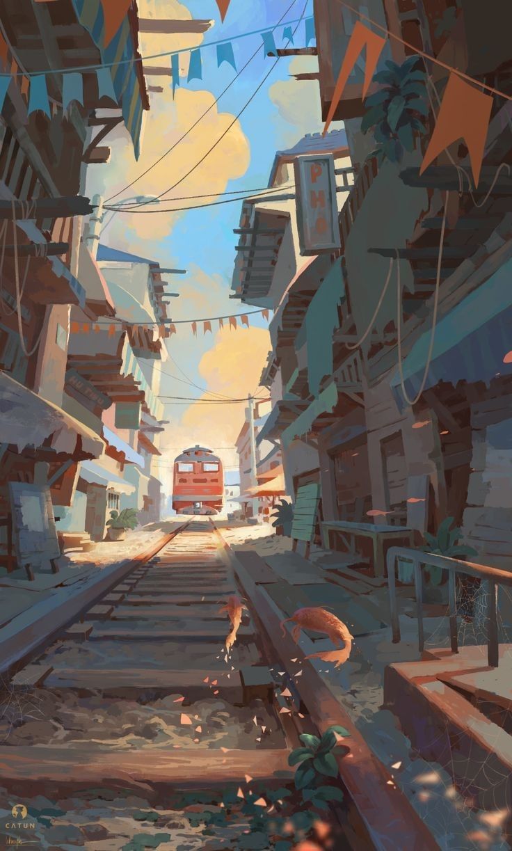 a train is coming down the tracks on a street, flanked by buildings. there are flags hanging overhead, and plants are growing in the foreground. there is a sense of morning light.