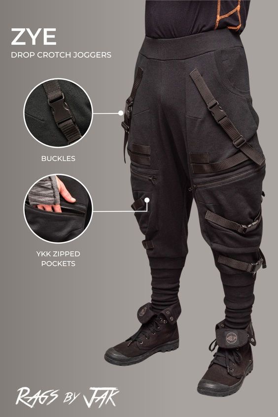 a model wearing a black pair of drop crotch joggers, called "zye" by the brand "rags by jak."  the joggers are made from a thick, black cotton blend and feature multiple pockets, straps, and buckles. the model is also wearing black boots.  the brand logo is prominently displayed at the bottom of the image.