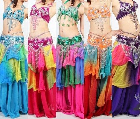five women are wearing vibrant and ornate belly dance costumes. each costume features a sequined bra top, a matching beaded belt, and a layered skirt in a rainbow of colors. the women are standing close together, showcasing the different color variations of the same style of costume.