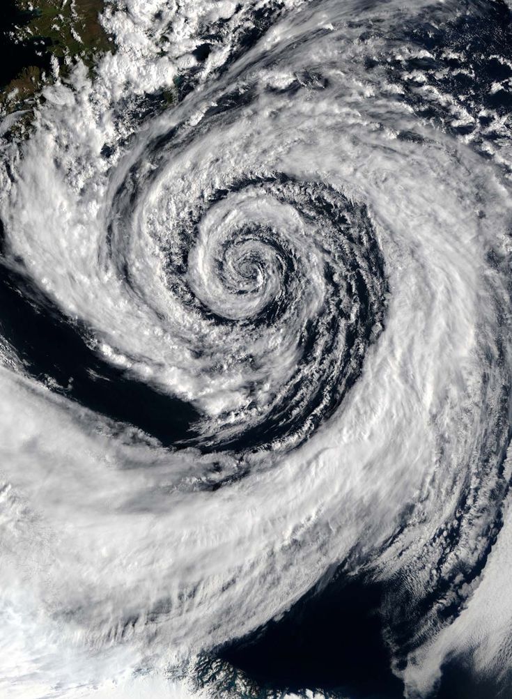 a satellite image of a swirling storm over the ocean. the storm is seen from above, with its clouds forming a spiral shape. the eye of the storm is visible in the center of the image. the image is taken from a satellite orbiting the earth. the ocean is a dark blue, and the clouds are white. the storm is a natural phenomenon that can be dangerous.