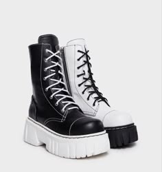a pair of black and white platform boots. the left boot is black with white stitching and the right boot is white with black stitching. both boots have white platform soles and are laceup.