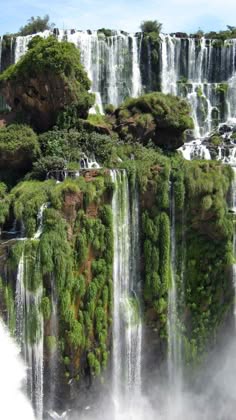 a cascading waterfall plunges down a lush, verdant cliffside, creating a breathtaking display of nature's power and beauty. the vibrant green foliage and the powerful rush of water create a sense of tranquility and awe. the image captures the essence of a tropical rainforest, with its exotic beauty and untamed wilderness.