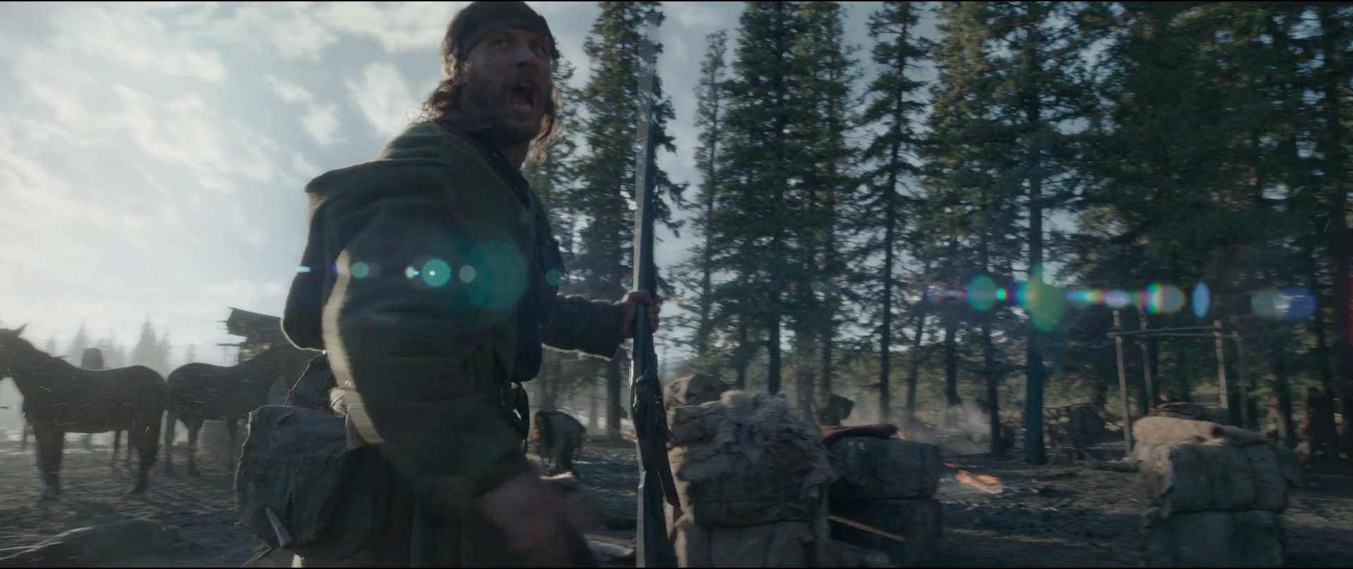 a scene from a movie or tv show depicting a battle or conflict in a forest setting. a soldier in a green uniform, holding a rifle, is the central figure, surrounded by other soldiers and horses. the overcast lighting and lens flare create a dramatic and chaotic atmosphere.