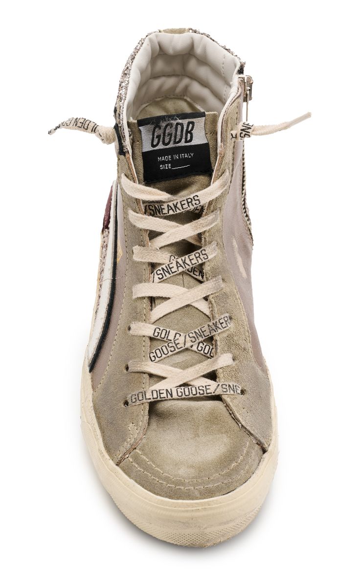 a closeup, studio shot of a pair of golden goose ggdb hightop sneakers. the sneakers are primarily beige suede with subtle grey accents. the laces are tied and feature repeated "golden goose/sneakers" branding.  the interior of the shoe is visible, showing the ggdb label and the "made in italy" stamp. the overall style is casual yet luxurious, showcasing the brand's characteristic distressed and worn look.  the shoes are presented on a white background.