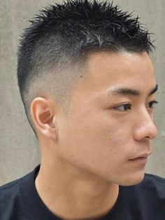 a closeup headshot of an asian male with a short, trendy haircut that features a fade on the sides and back. the man has short, dark hair and a neutral expression. the lighting is soft and diffused, highlighting the details of his haircut and facial features. the background is blurred, drawing attention to the subject.
