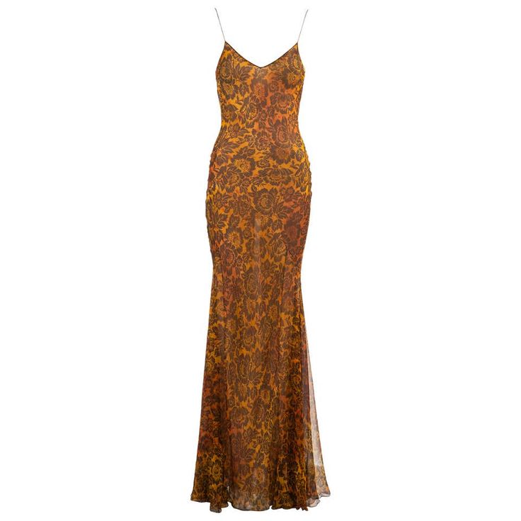 a long, silky, sleeveless dress with a floral pattern in shades of yellow, orange, brown, and black. the dress is a slip style, with a fitted bodice and a flowing skirt that falls to the floor. it is a beautiful and elegant dress, perfect for a special occasion.