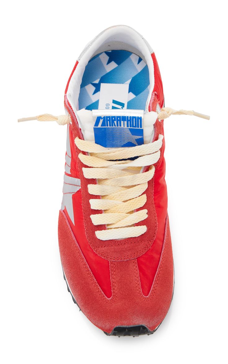 a closeup topdown view of a single red golden goose marathon sneaker.  the shoe is predominantly red suede with white and blue accents, including a blue "marathon" label on the tongue and a star pattern on the inner lining.  the laces are a light beige color. the shoe is isolated on a white background.