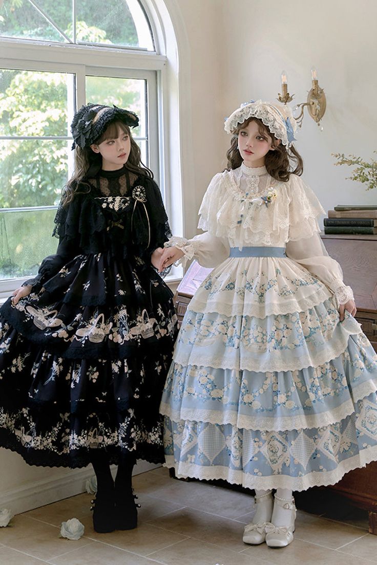 the image shows two women dressed in elegant lolita fashion, standing in a room bathed in soft, natural light streaming in from a window. one woman wears a black dress adorned with a delicate floral print, while the other is dressed in a similar style but in a light blue with a contrasting white top. both outfits are intricately detailed with lace, ruffles, and petticoats, adding to the dreamlike and romantic atmosphere of the scene. they both wear matching bonnets, completing their coordinated lolita looks.