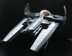 a studio photograph of a science fiction spaceship model against a black background. the spaceship is silvergrey with black accents. the model appears to be highly detailed with cockpit, engines, and weapon systems.