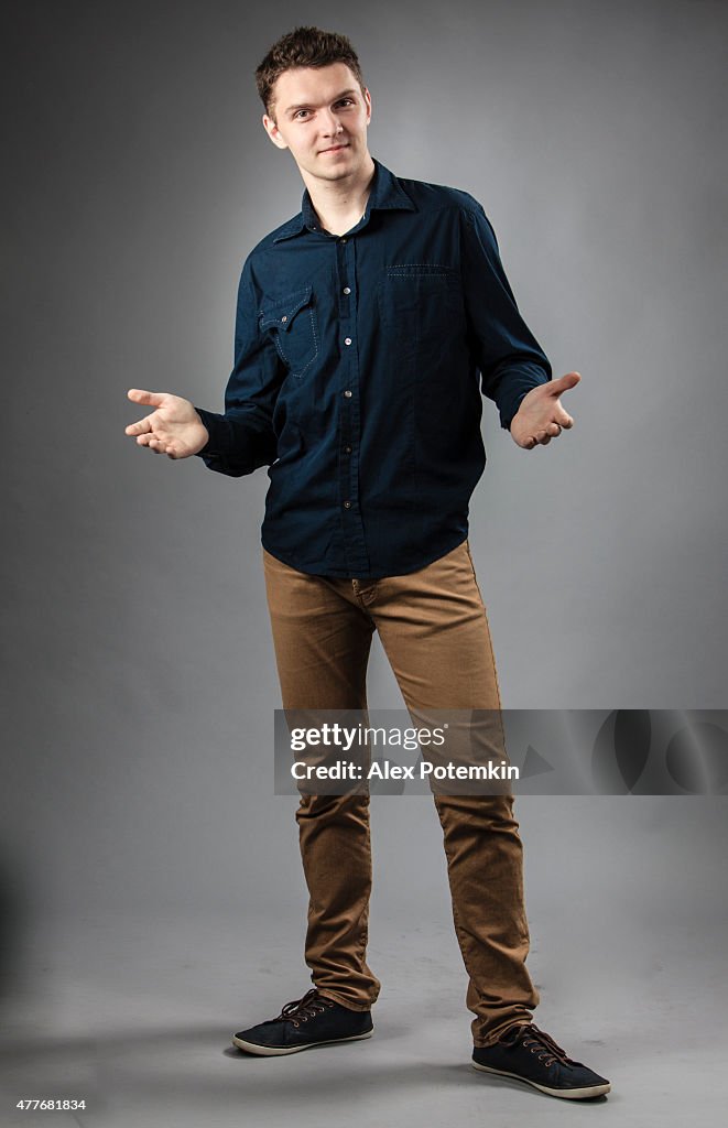 a man in a dress shirt and jeans stands with open hands and a slight smile.