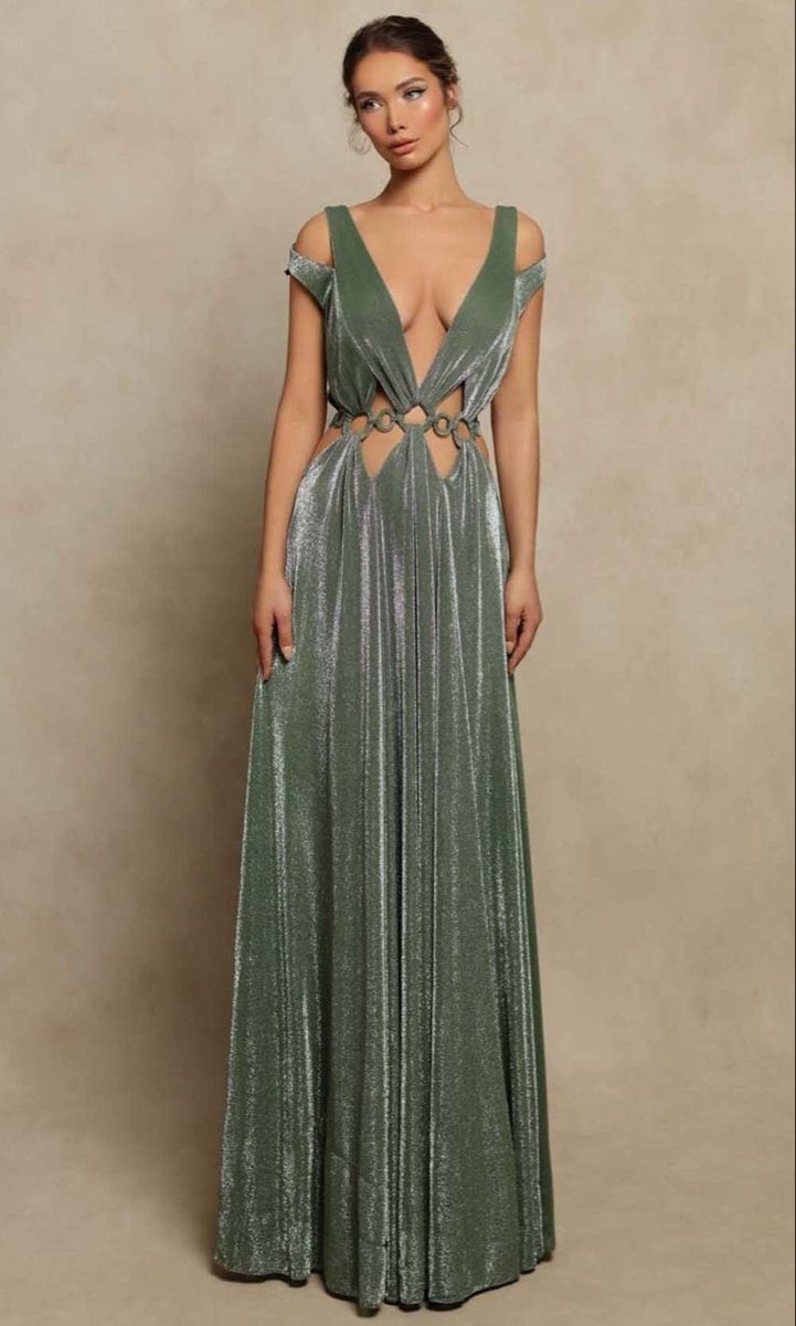 a fulllength studio shot of a woman model wearing a flowing, olive green maxi dress. the dress has a plunging vneckline, cutout details at the waist, and a metallic shimmer. the background is a neutral beige color. the woman is standing and posing for the photograph.