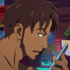 the image shows a man with brown hair and a beard looking concernedly at his phone. he is shown from the chest up and is positioned on the left side of the image. the background is blurred, but appears to be an indoor setting with bright, colorful lights.