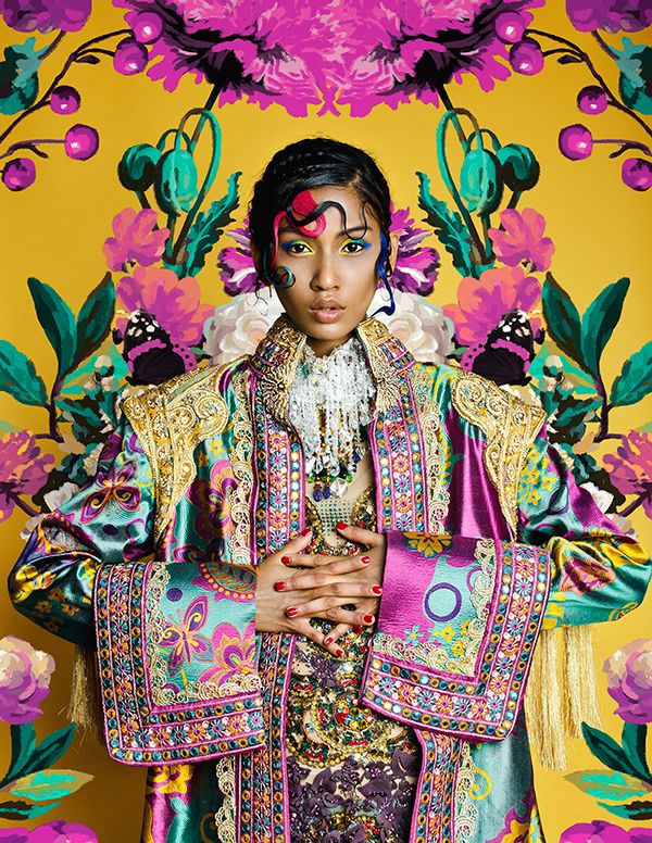 a closeup portrait of a woman in an elaborate, richly colored, embroidered garment.  the clothing is a vibrant mix of teal, magenta, gold, and other jewel tones, with intricate paisley and floral patterns. her makeup is equally bold, featuring vibrant colors and stylishly arranged braids. the background is a striking collage of yellow and floral elements that complements the clothing's rich colors and patterns. the overall impression is one of artistic fantasy and traditional cultural clothing. the image has a high level of detail and appears to be a professional studio shot.