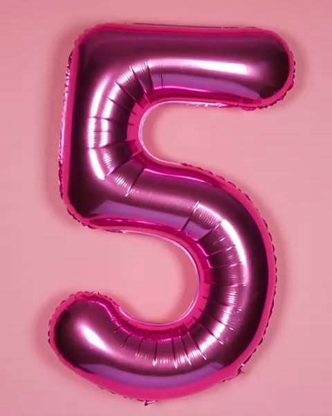 a shiny pink number 5 foil balloon against a pink background. the balloon is metallic and reflects light, and it's designed as a party decoration.