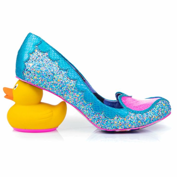 a whimsical high heel shoe is supported by a yellow rubber duck on a white surface. the shoe is predominantly blue with a glittery texture, featuring a pink patch at the toe and a scalloped design along the upper edge. the rubber duck is a bright yellow with an orange beak and a pink base. the composition creates a playful and eyecatching image.