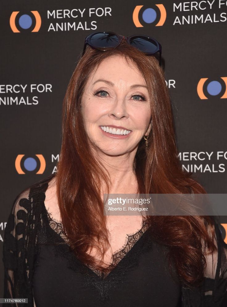 a red haired woman wearing a black lace dress smiles at the camera at a mercy for animals event.