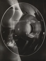 the photograph is a striking black and white image that appears to be a surreal or abstract representation of a female nude. the figure's body is partially visible, its form distorted and fragmented by its reflection in a large, curved glass object – possibly a bowl or a lens.  the glass piece dominates the frame, creating multiple reflections and refractions, making the form of the body both visible and obscured. the interplay of light and shadow creates a strong sense of depth and texture, emphasizing the curves and contours of both the body and the glass. the overall effect is one of both sensuality and mystery.