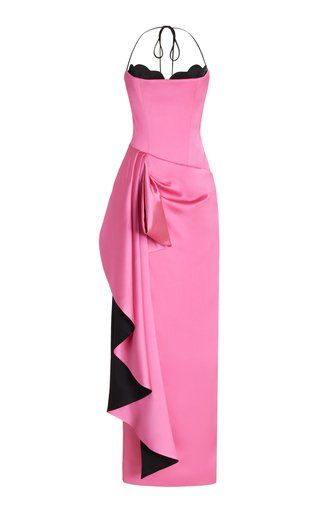 a pink satin halter top evening gown with a draped detail and black lining is shown on a white background. the gown has a fitted bodice and a long, flowing skirt. the halter top is secured with black straps. the draped detail is on the left side of the skirt. the lining of the drape is black.