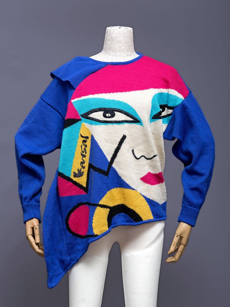 a mannequin wearing a colorful graphic knit sweater with an asymmetric hem.