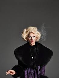the image is a highfashion studio portrait of a drag queen. she is striking a pose, holding a cigarette, and dressed in a glamorous outfit.  the queen sports a voluminous blonde wig and a large, black fur coat. her makeup is bold, featuring bright red lipstick. the background is a simple, dark grey, drawing all the attention to the subject. the overall mood of the photo is dramatic and stylish, reminiscent of classic hollywood glamour.