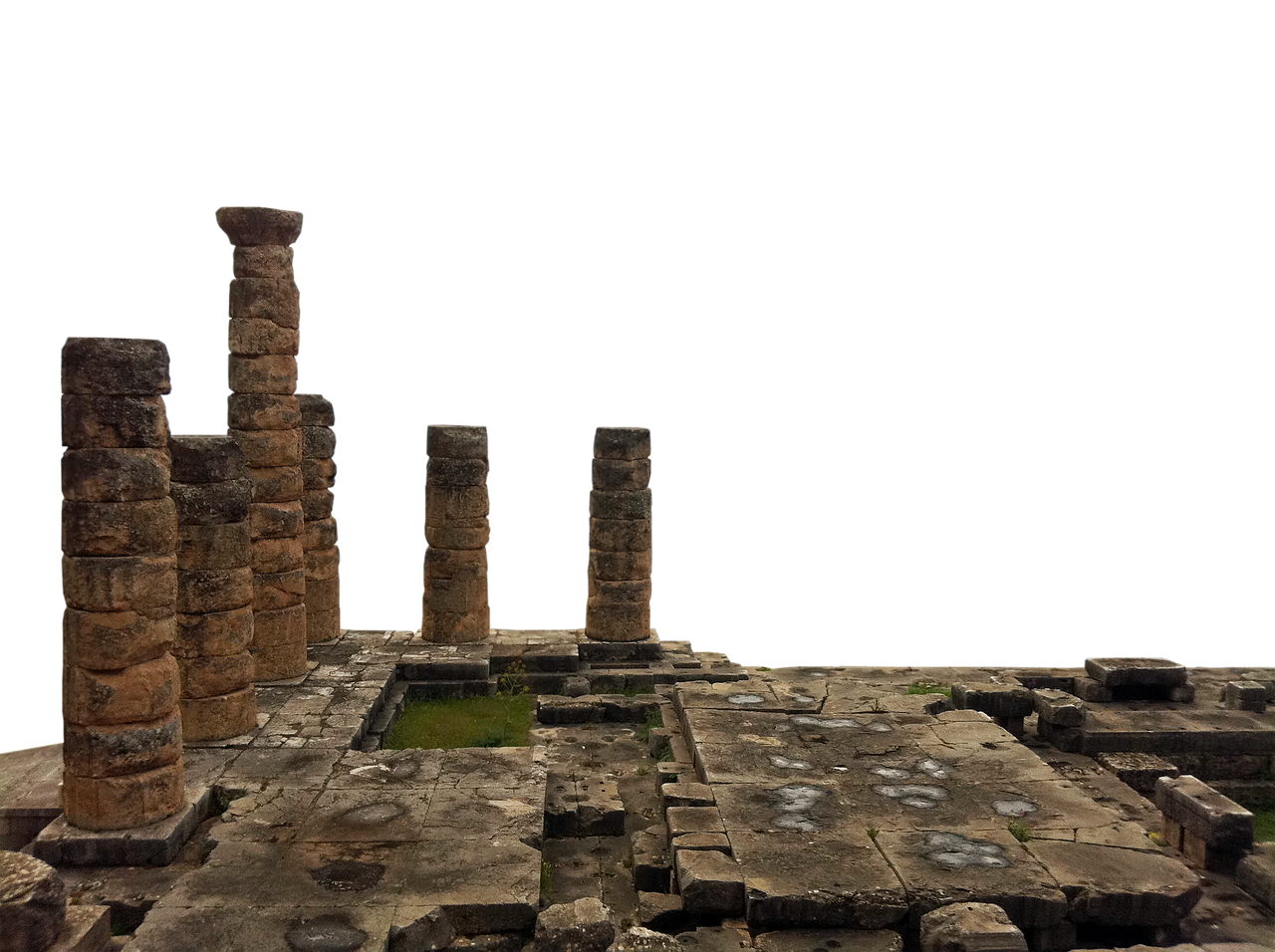 the image shows a set of ancient stone columns and ruins, likely part of an archaeological site. the columns are made of stacked, weathered stones. the ground is covered with stone slabs, some cracked and broken, with small patches of grass growing in the gaps. the background is solid black. the image conveys a sense of history and decay.