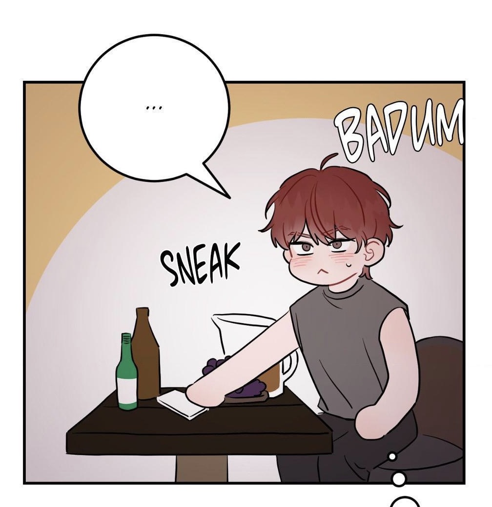 he image is a panel from a manga or webtoon. it features a cute, blushing boy with reddishbrown hair sneaking something from a table. the table has bottles of alcohol (wine and soju) and a pitcher of something.  there are speech bubbles indicating his actions ("sneak") and his inner feelings ("badum"). the art style is clean and expressive.
