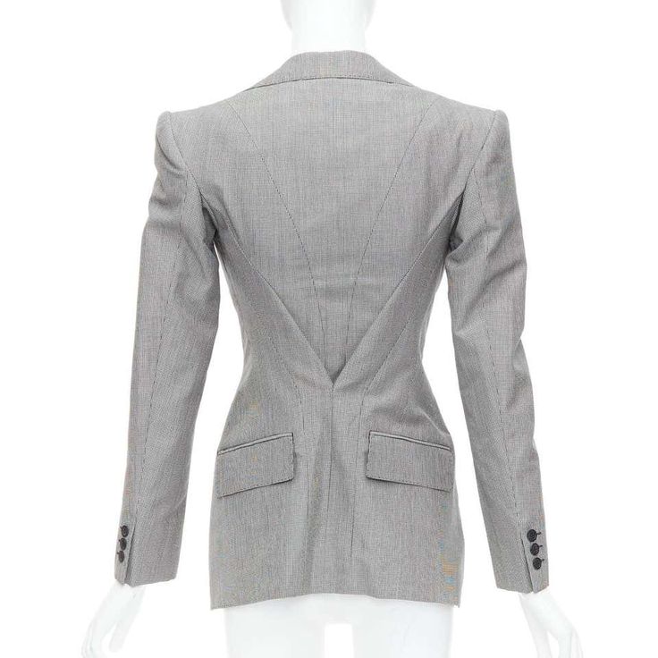 a grey pinstripe blazer with a fitted silhouette and a double breasted closure. the blazer has a pointed lapel and features a single button closure at the bottom. the blazer is fully lined and has two patch pockets on the front. the blazer is made of high quality materials and is perfect for a formal occasion.