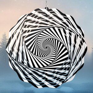 a hanging decoration with a black and white spiral optical illusion pattern against a blurred wintery background.