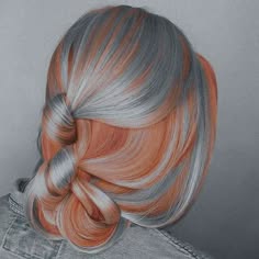 a closeup of a woman with silver and pink ombre hair. her hair is styled in a loose bun, and she is looking to the right of the frame. her hair is styled in an ombre fashion with the silver hair on top and the pink on the bottom. she is wearing a denim jacket.