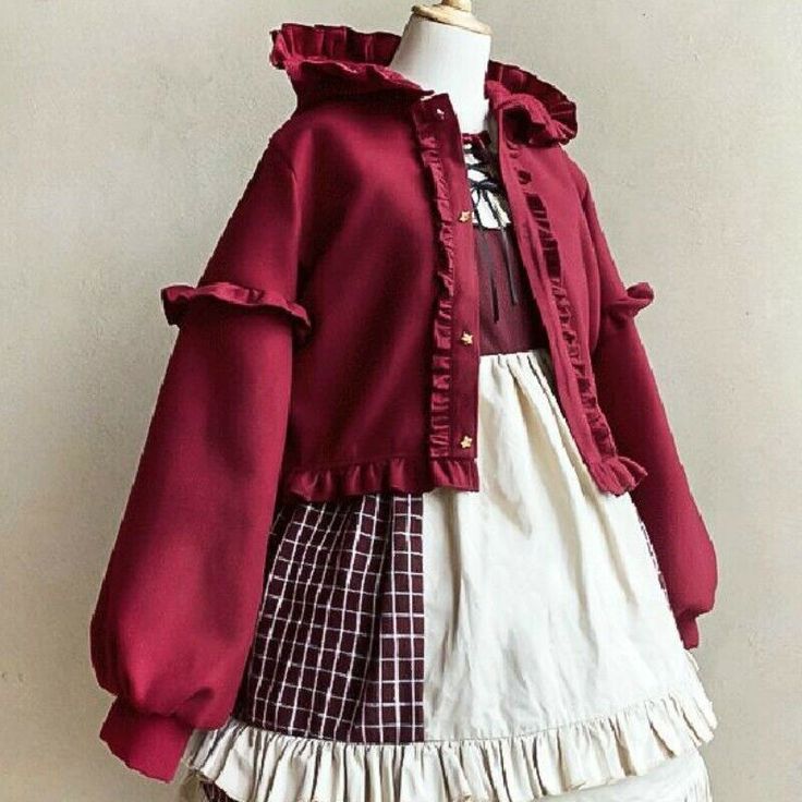 a red ruffled jacket is displayed over a white dress with a red and brown plaid skirt. the jacket has a hood, gold buttons, and ruffled trim. the dress has a white lacetrimmed top and a ruffled hem. the outfit is styled in a lolita fashion.