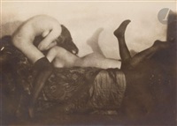 the photograph depicts two nude women in a tender embrace. one woman is positioned in a crouching posture with her head bowed, while the other lies back, her legs extended.  the image is softly focused, creating a dreamy and intimate atmosphere. the sepia tone and the use of shadows enhance the mysterious and sensual quality of the scene.  the women’s bodies are captured with a focus on curves and form. the background includes dark drapery or fabric, which adds to the overall mood.  the overall style suggests a vintage art photography piece, possibly from the early to mid20th century.