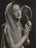 the black and white photograph is a striking studio portrait of a woman. she is elegantly draped in a lightcolored fabric that covers her head and shoulders, almost like a shawl or veil.  her gaze is soft and slightly downcast, giving a pensive mood. she holds a hand mirror, and her reflection is partially visible, creating a sense of introspection. the lighting is dramatic, with chiaroscuro effects highlighting her features and the folds of the fabric. the overall style suggests a 1930s or 1940s aesthetic, typical of fashion or portrait photography from that era. the image’s focus is on the woman's serene yet expressive countenance and the interplay of light and shadow.