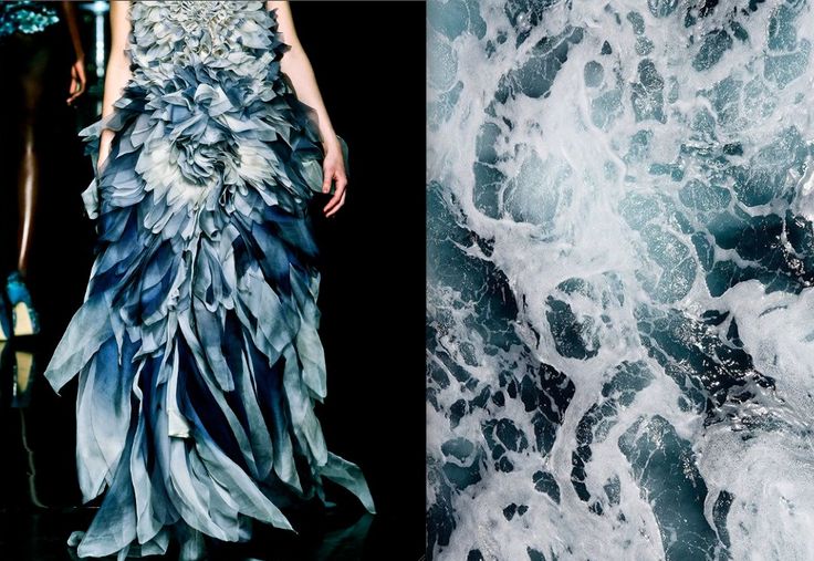 a woman in a blue dress on a runway. the dress looks like the waves of an ocean. the dress is made of layers of fabric and has a flowing, ethereal look. the woman is standing on a dark stage, and the dress looks even more striking against the dark backdrop. the dress is a beautiful example of how fashion can be inspired by nature. the image of the waves is in the background and the dress is in the foreground.