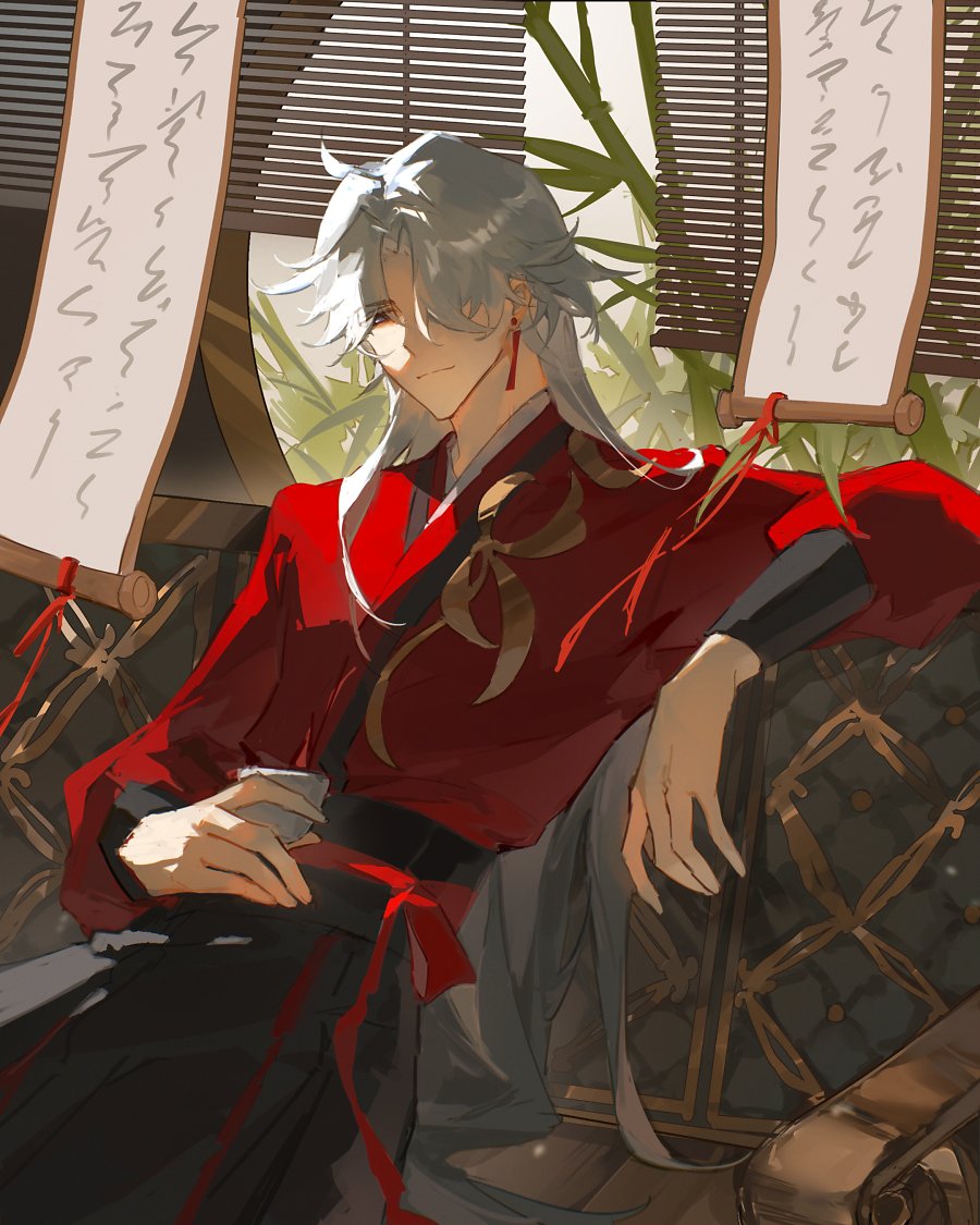 an anime boy with long white hair, wearing a traditional red robe, is sitting on a wooden chair. he has a calm expression and his eyes are closed. behind him are  scrolls with writing and a plant. the  background is blurred and the image looks like it's from an anime.