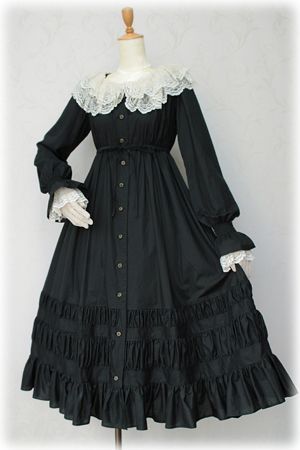 a black lolita fashion dress is shown on a mannequin against a plain gray background. the dress features a square neckline, long sleeves with lace trim, a buttonfront closure, and a full, ruffled skirt. the dress is accented with a white lace collar. the studio lighting highlights the details of the dress and creates a dramatic effect.