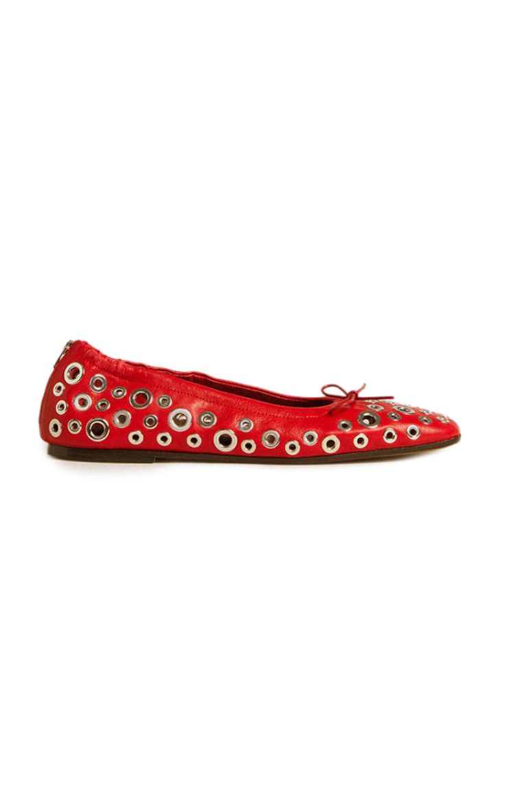 a pair of women's red leather ballet flats with silver metal eyelets are shown against a white background. the shoes are positioned at a slight angle, and the focus is sharp. the eyelets are evenly spaced across the shoes, and the shoes appear to be in new condition.