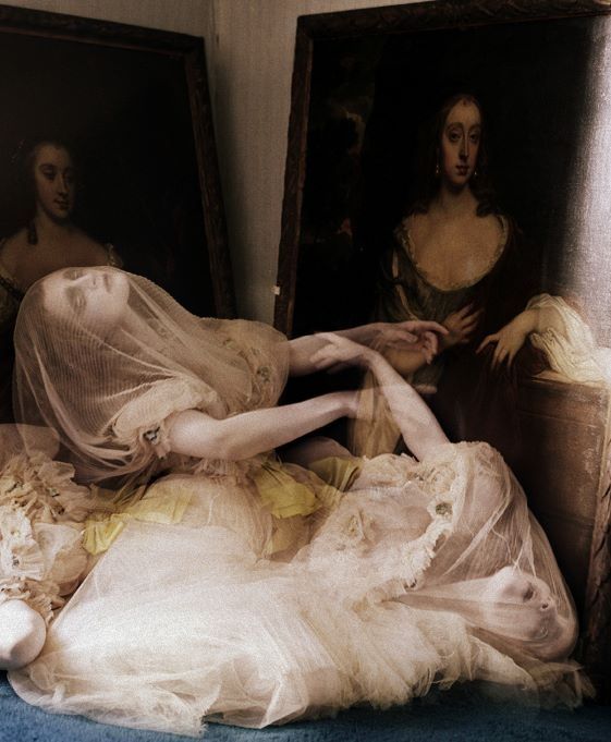 the image shows two women in ethereal white and lightcolored dresses, partially covered with translucent veils. they are positioned in front of two antique portraits of women. the dresses are layered with lace and tulle fabrics, creating a soft, flowing appearance. the veils obscure the features of the women, adding to the dreamlike quality of the image. the overall impression is one of classical elegance and serenity, juxtaposed with a sense of mystery.