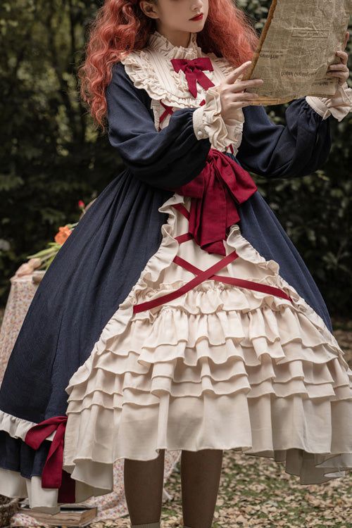 a woman in an elegant lolita dress stands in a forest holding an open book.  her dress is navy blue and cream with red accents, and she is wearing a white lace blouse underneath. she has long red hair and is looking down at the book. the background of the image is a lush forest with green trees and plants. the lighting in the image is soft and natural, giving the scene a dreamy and romantic feel.